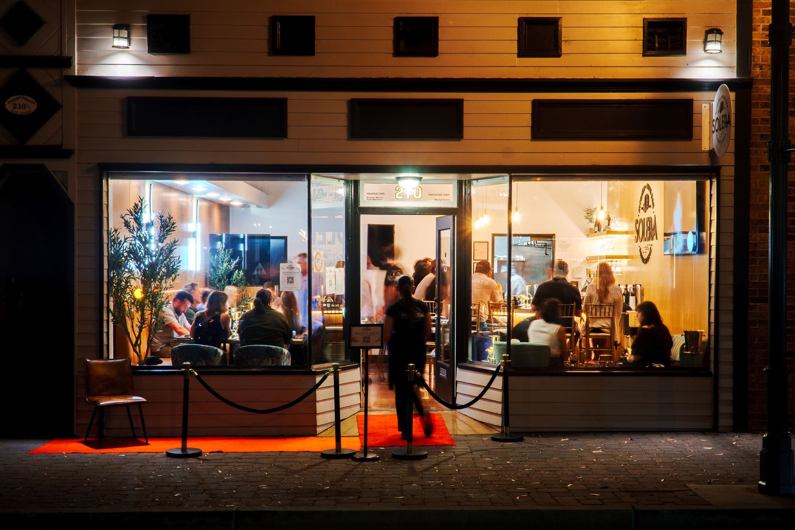 Solera's storefront glowing at night on Main Street in Seal Beach