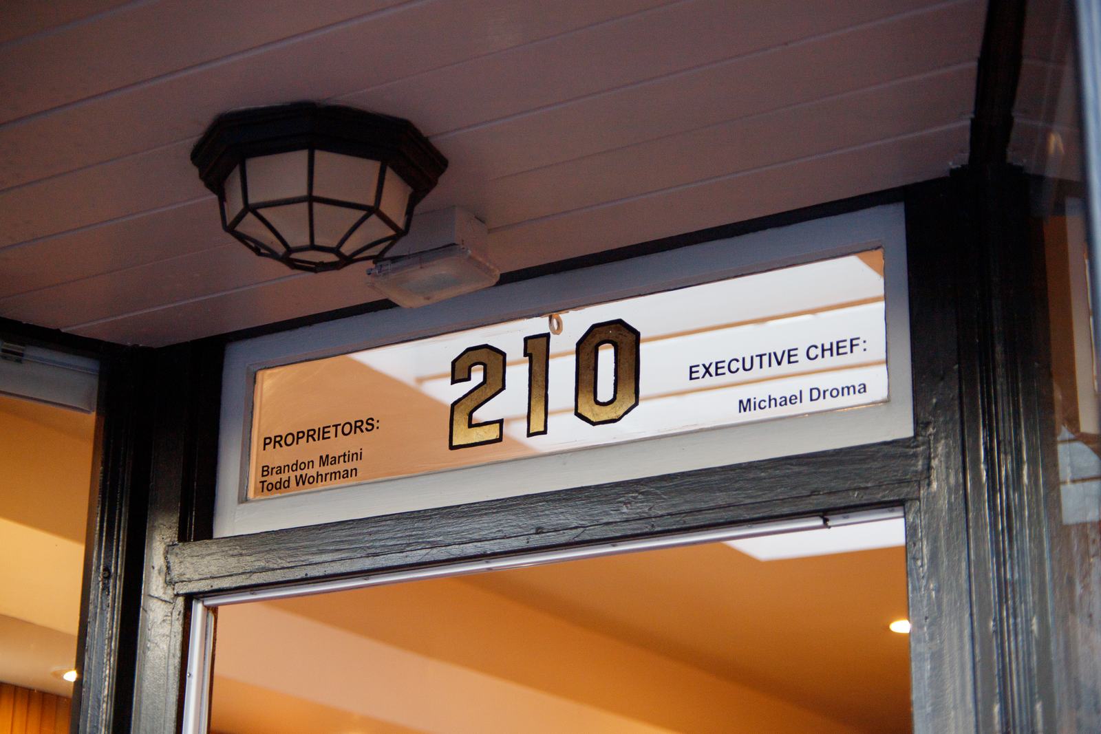 The gold 210 transom sign above Solera's front door, listing proprietors Brandon Martini and Todd Wohrman and Executive Chef Michael Droma